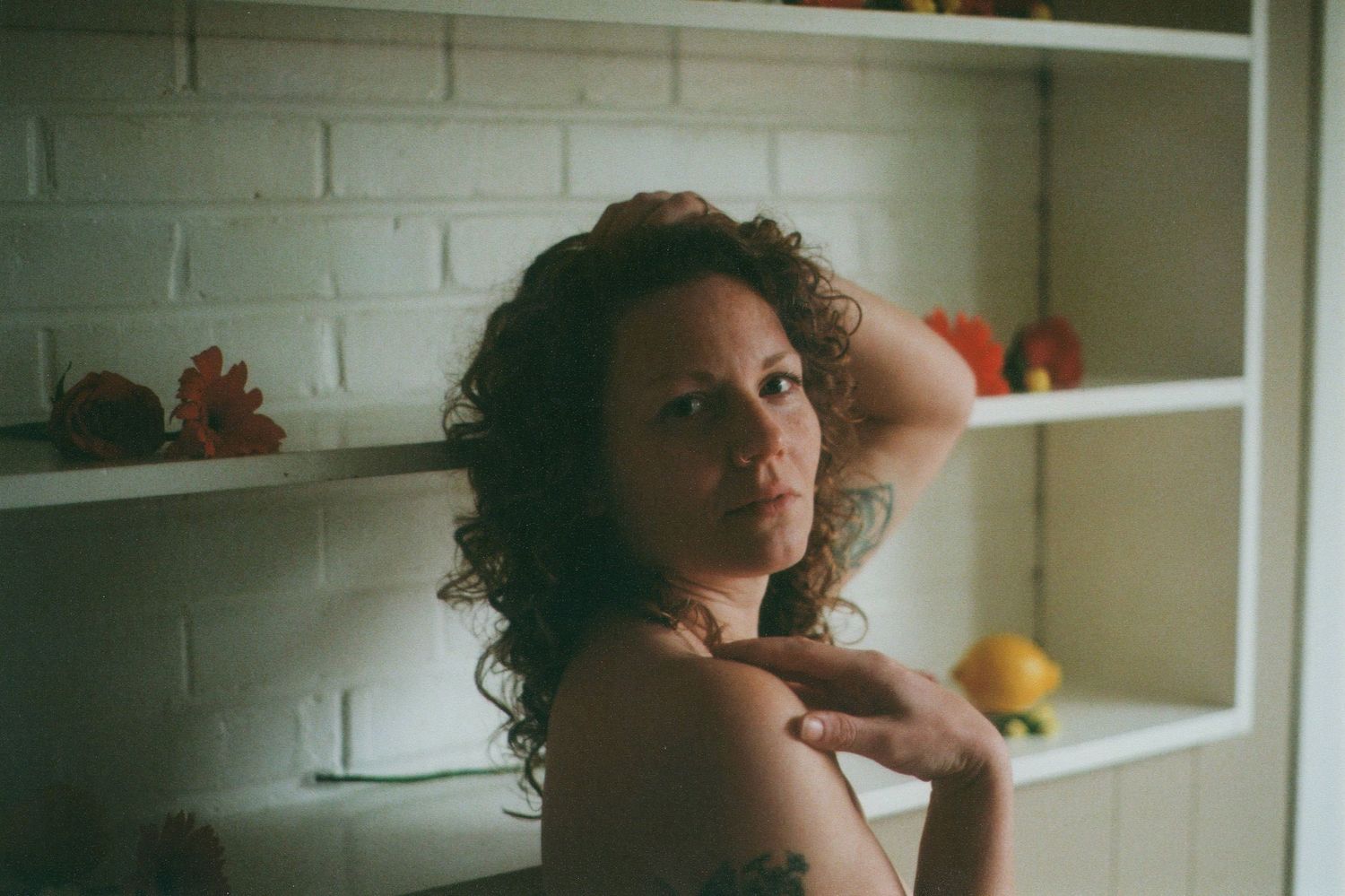 Intimate boudoir portrait with moody lighting and white brick wall background.