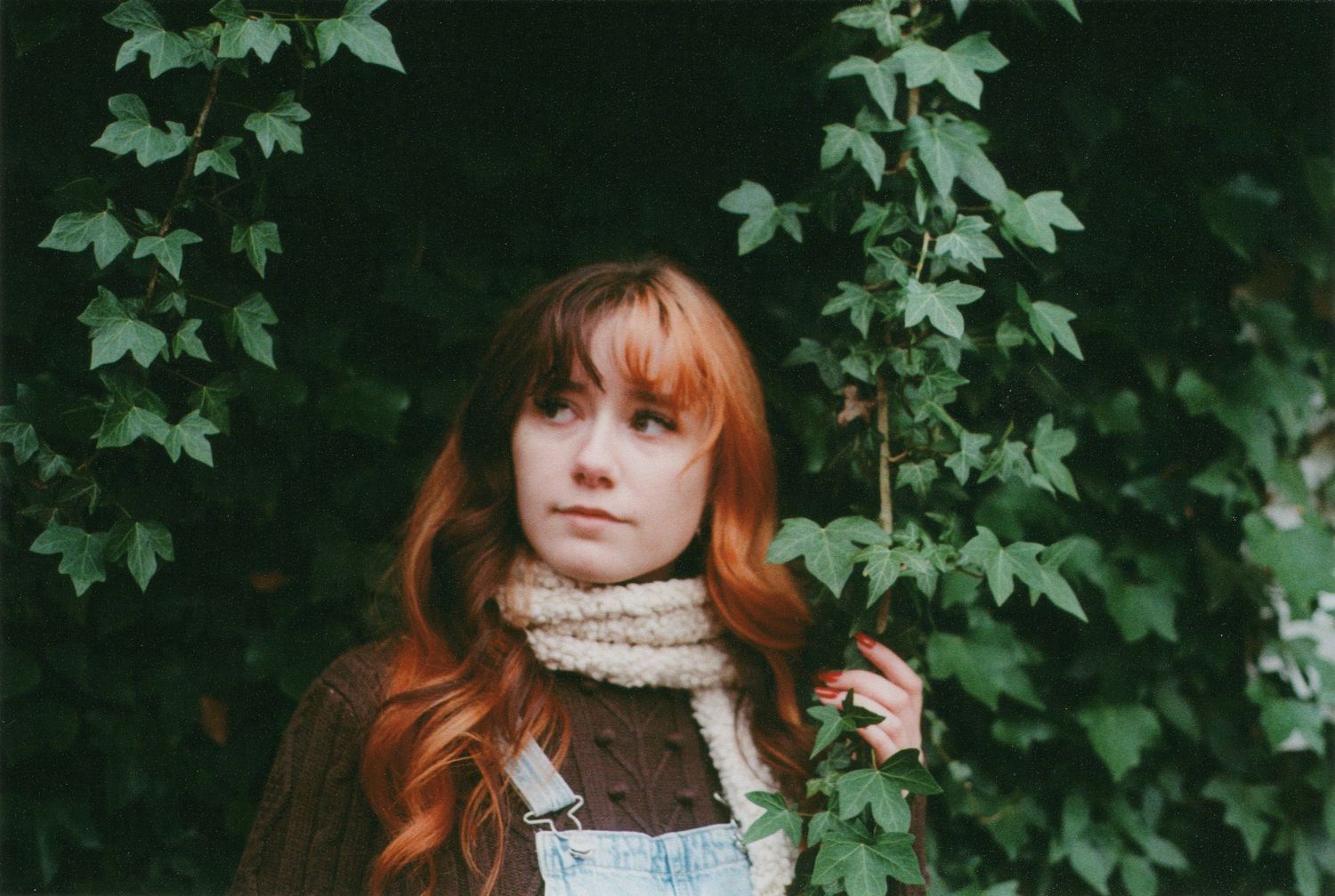Portrait in woodland setting with ivy vines and chunky knit scarf.