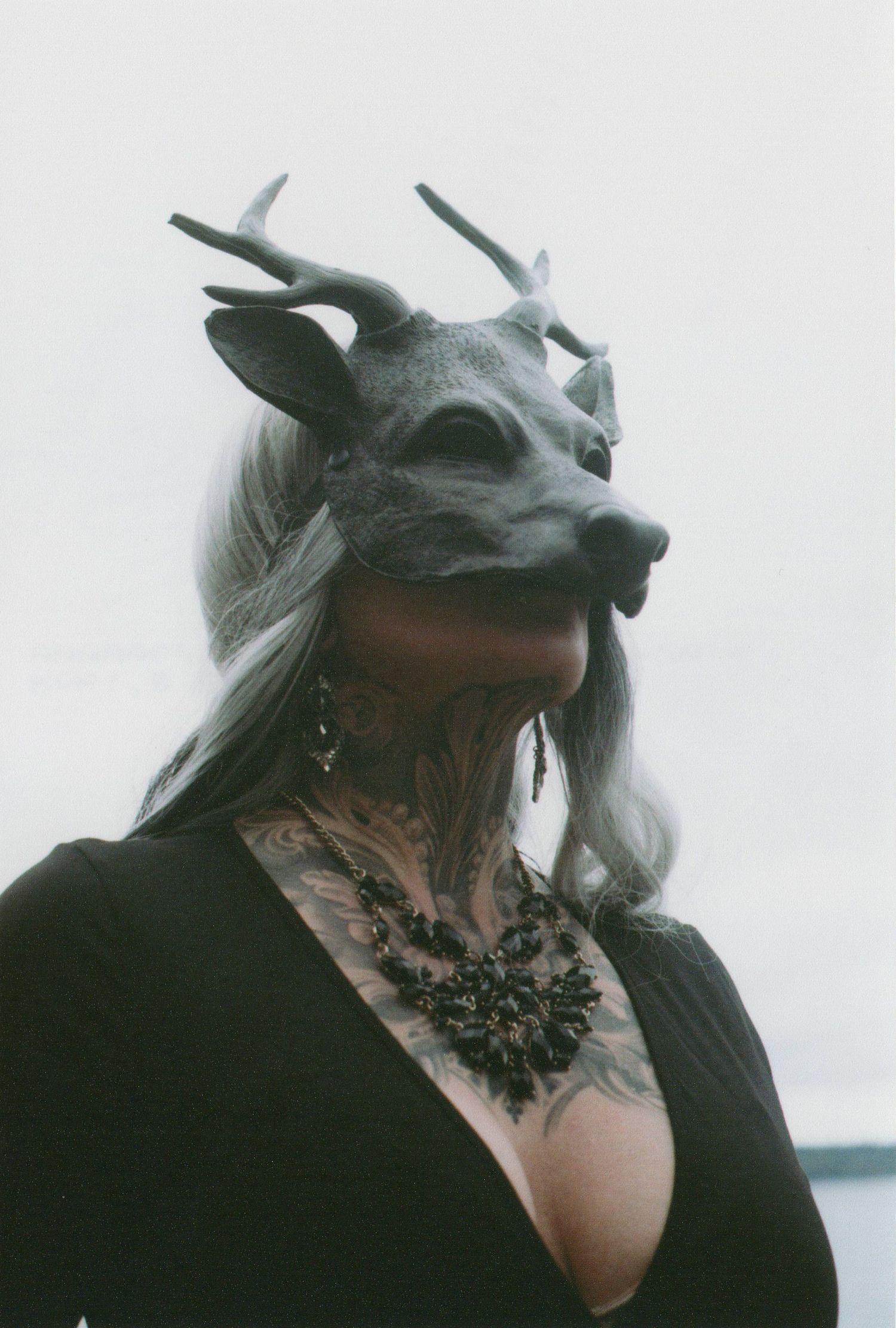 Artistic portrait wearing grey deer mask and black lace choker.