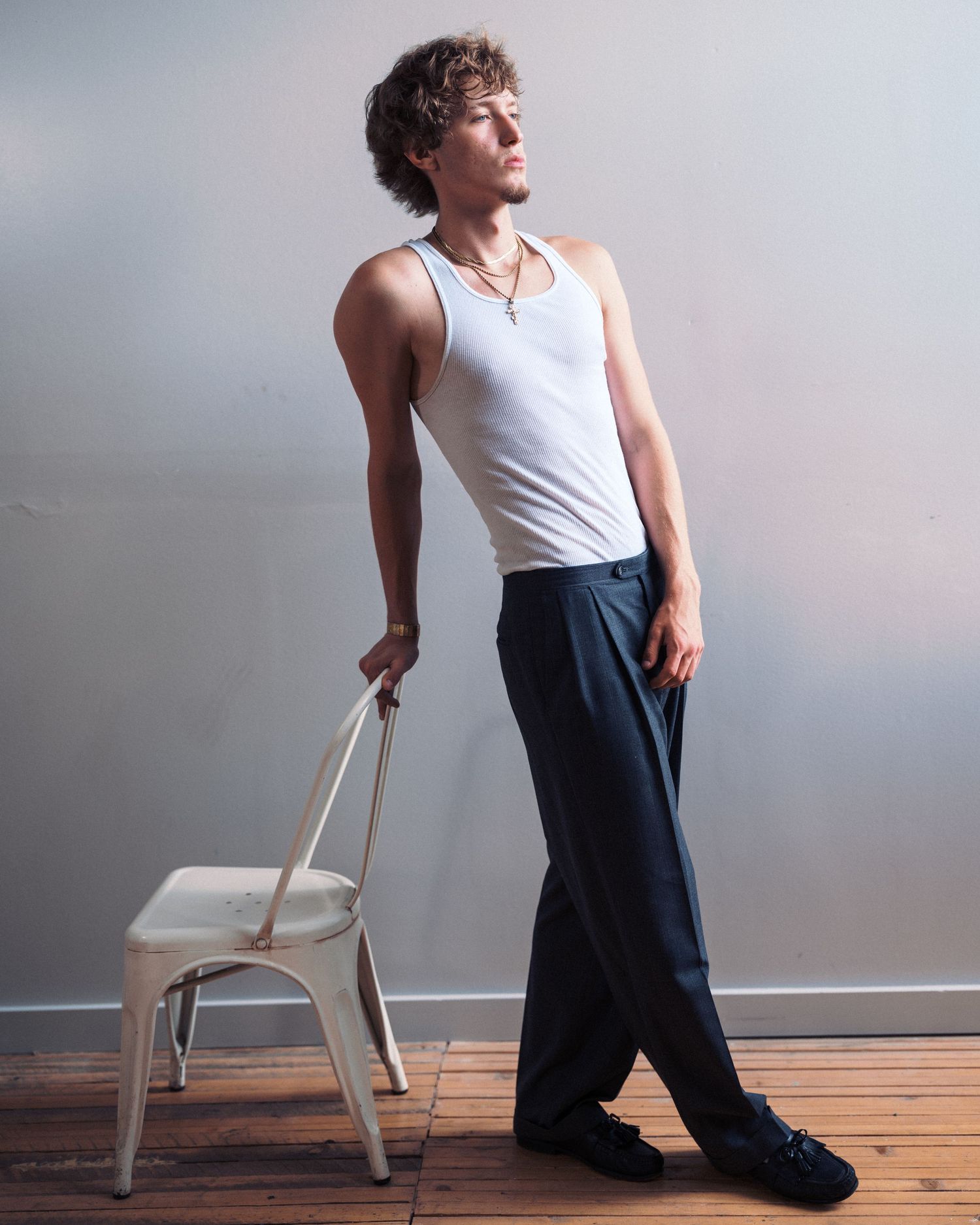 Someone strikes creative dance poses with a white chair against a neutral background in a multi-shot series.