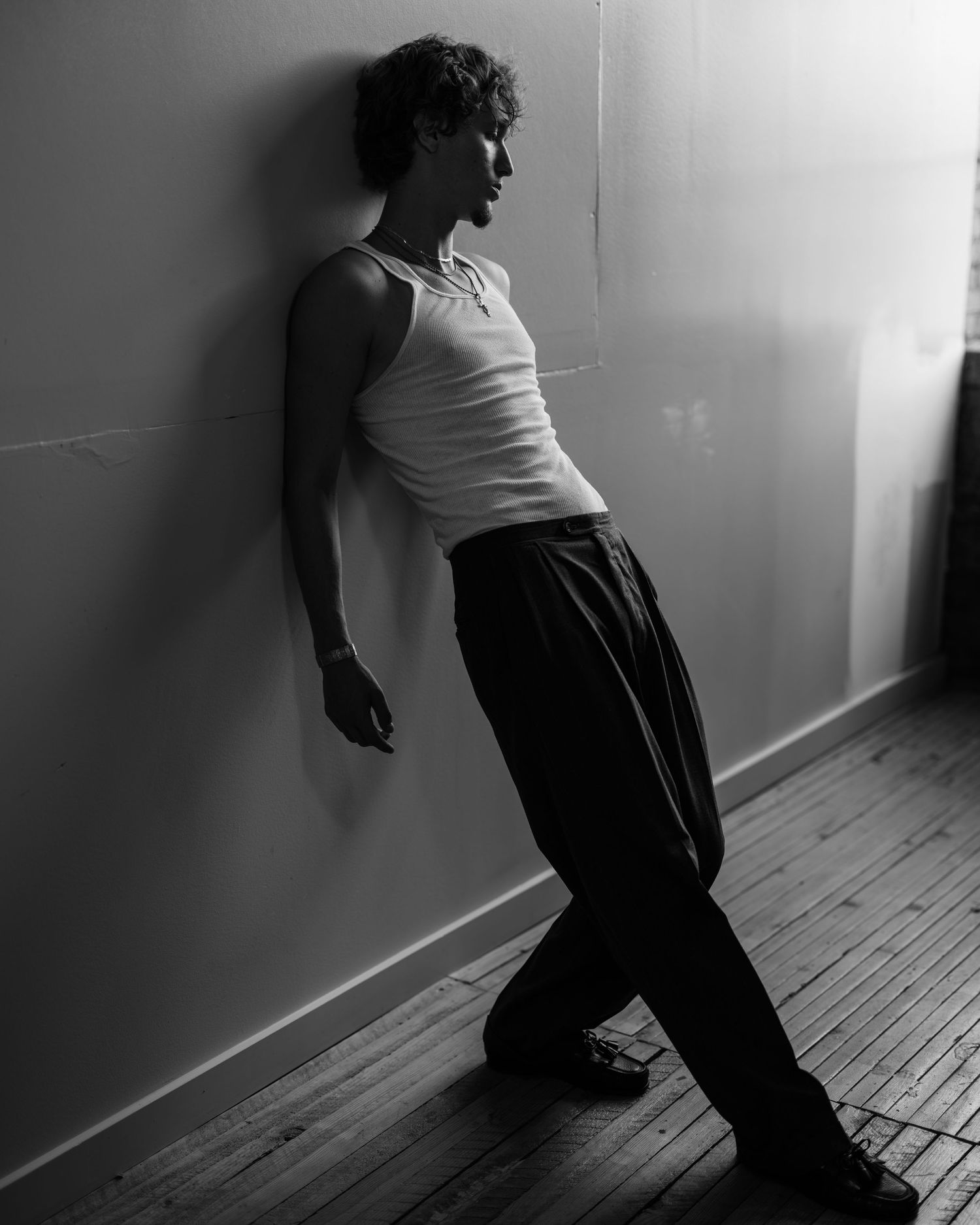 A series of moody black and white photos showing a figure leaning against a shadowy wall in different positions.