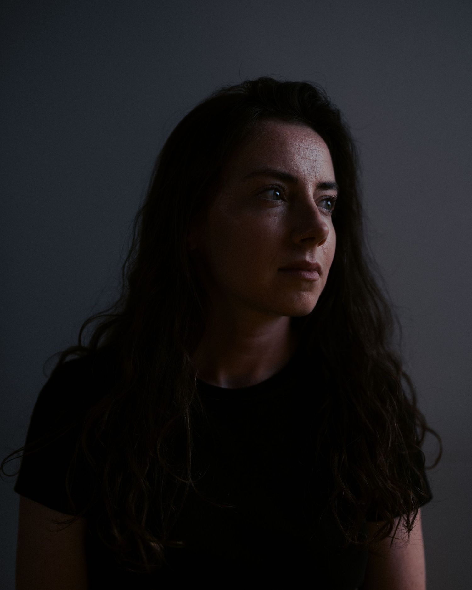 A dark moody series of portraits shows a person with long dark hair in low-key lighting against a black background.