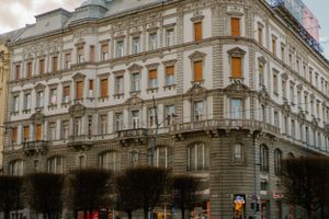 Historic corner apartment building with ornate architectural details and illuminated windows in a European city.