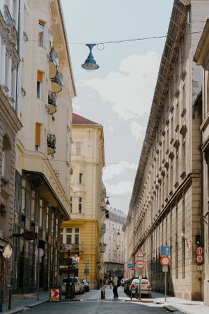 Historic street view in Prague with ornate architecture, yellow buildings, and vintage lamp post hanging over cobblestone road.