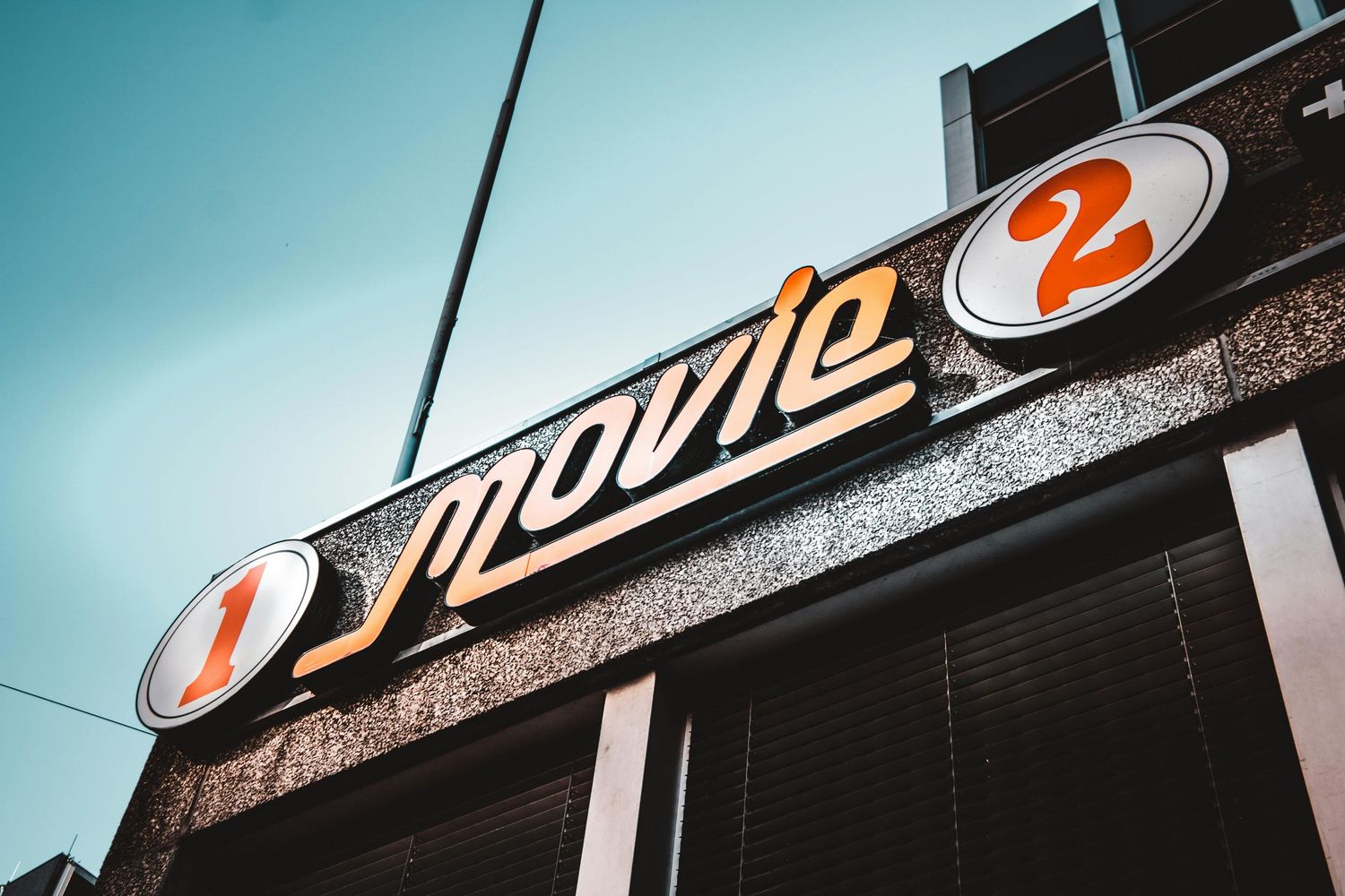 A retro movie theater sign reading "Movie 2" against a teal sky background.