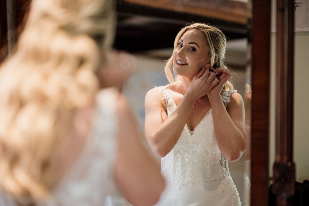 A bride wearing a classic white wedding dress reacts emotionally while reading a letter before her ceremony at Oxnead Hall in Norfolk.