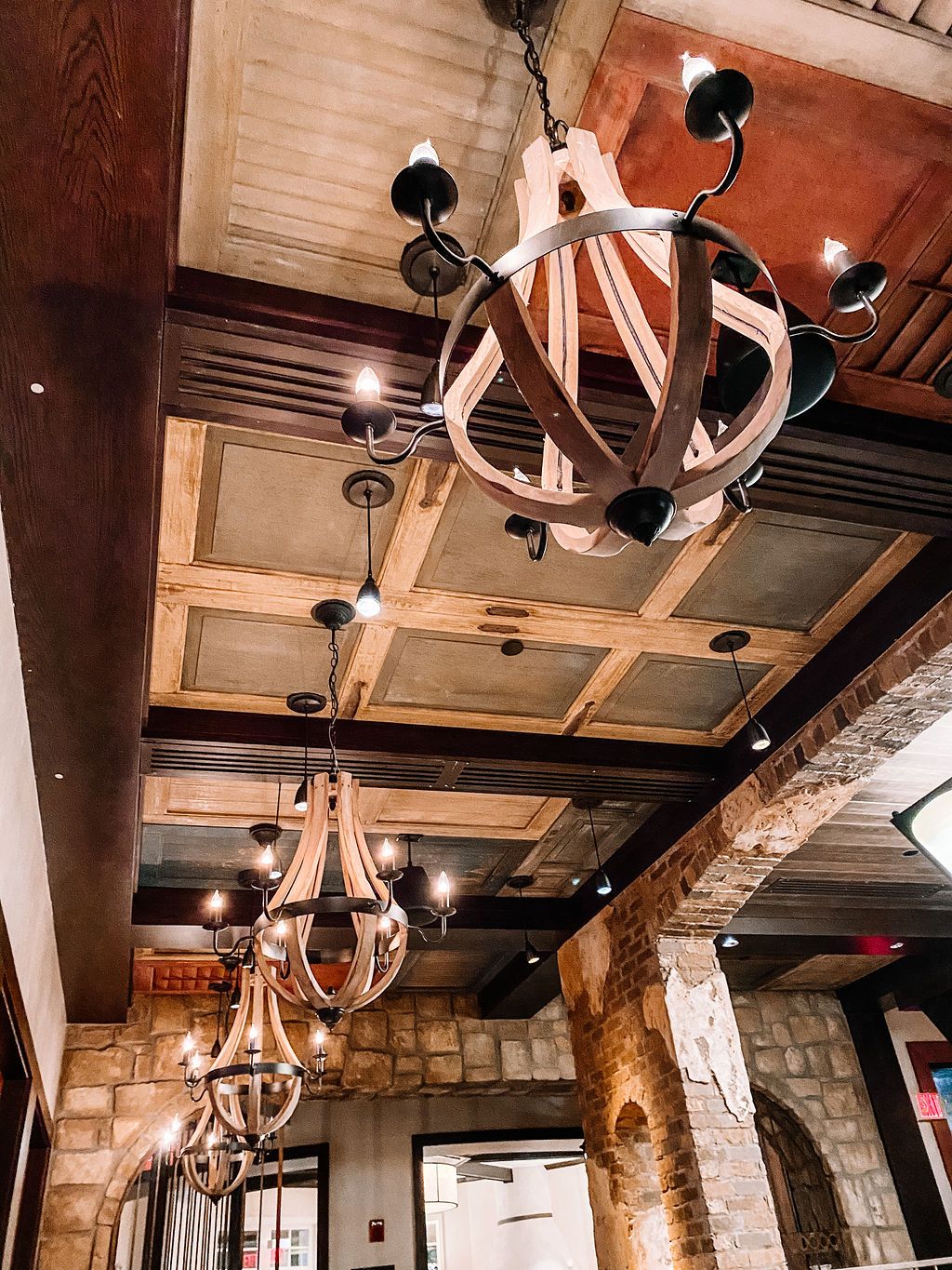 Rustic wooden ceiling with circular wrought iron chandeliers and exposed beams.