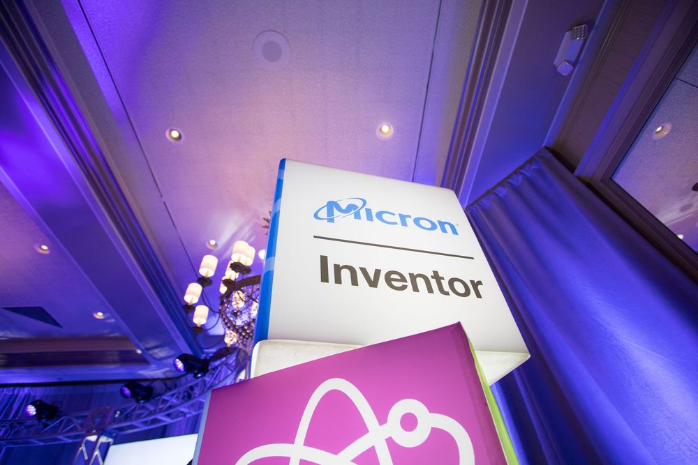 Purple and blue lighting illuminates a modern tech conference or event space with corporate signage and displays.