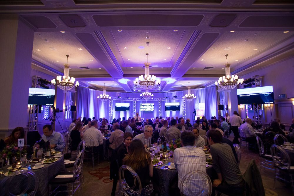 Large indoor event space with purple uplighting and chandeliers showing multiple views of a formal banquet setup.