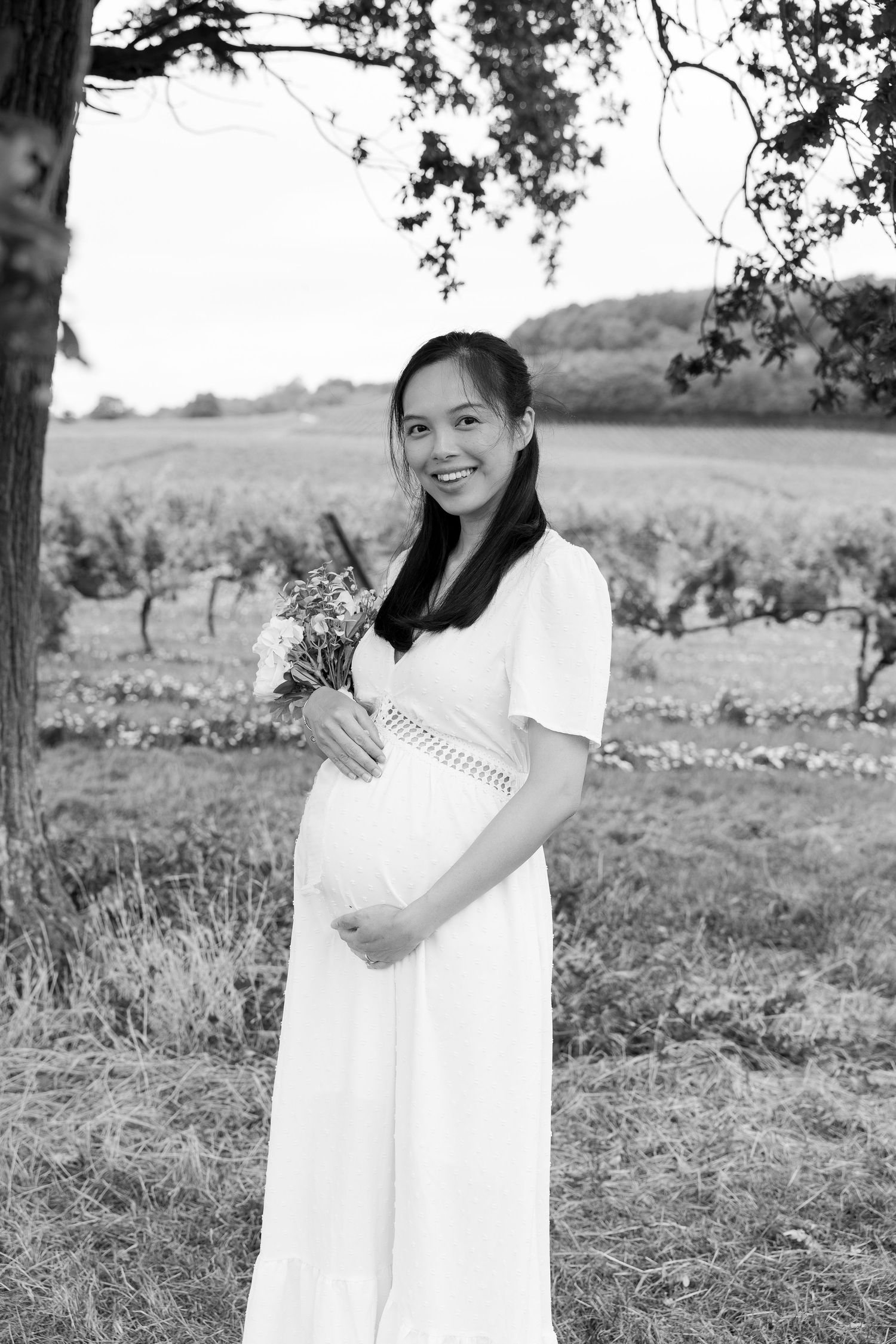 Black and white photo series showing a person in a flowing white dress embracing notes and books in a grassy field.
