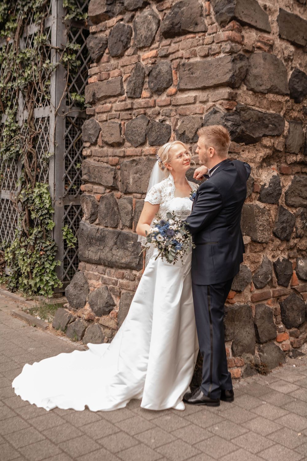A sequence of five romantic wedding photos showing a couple embracing against a rustic stone wall background.