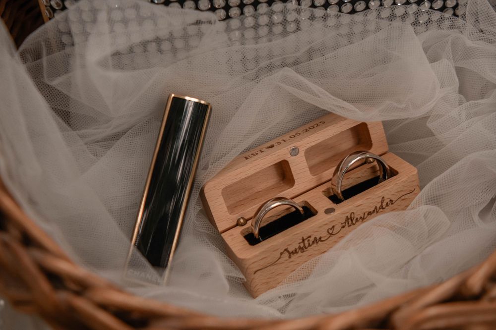 A wooden USB drive box with laser engraving lies next to a black USB drive on white tulle fabric.