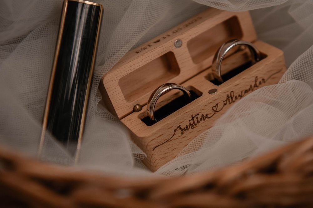 Wooden wedding ring box with custom engraving and metal accessories in warm lighting.