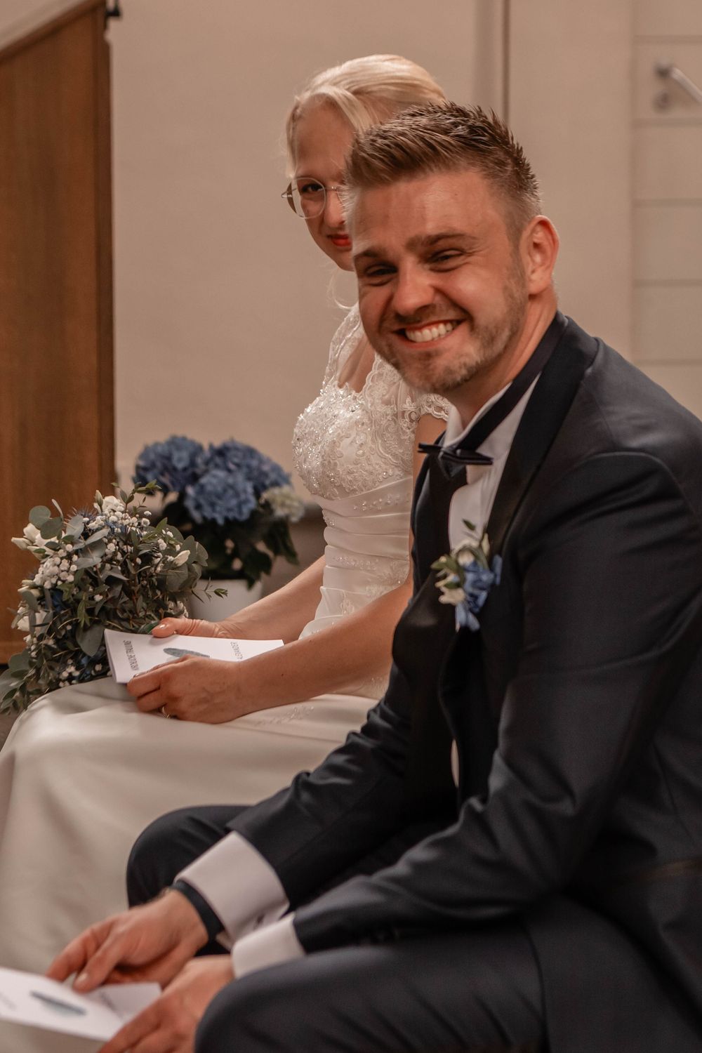 A happy couple signs their marriage documents during an intimate wedding ceremony with an elegant decor.