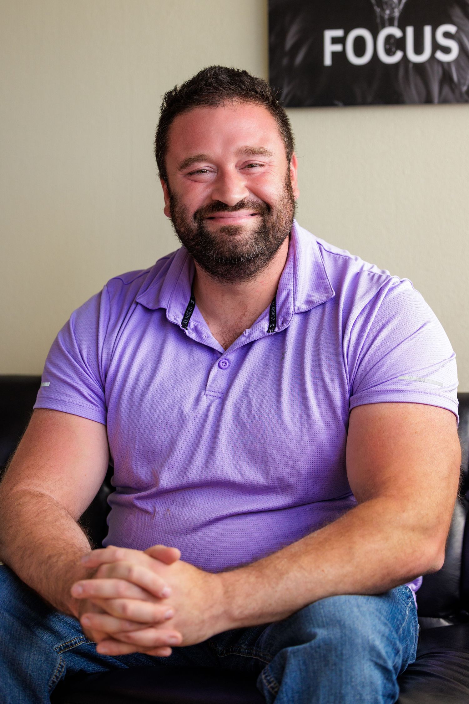 A person wearing a purple polo shirt sits casually on a couch, shown in a series of similar poses.