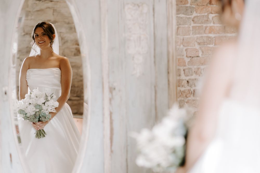 Two bridal bouquets with white flowers resting against an exposed brick wall.