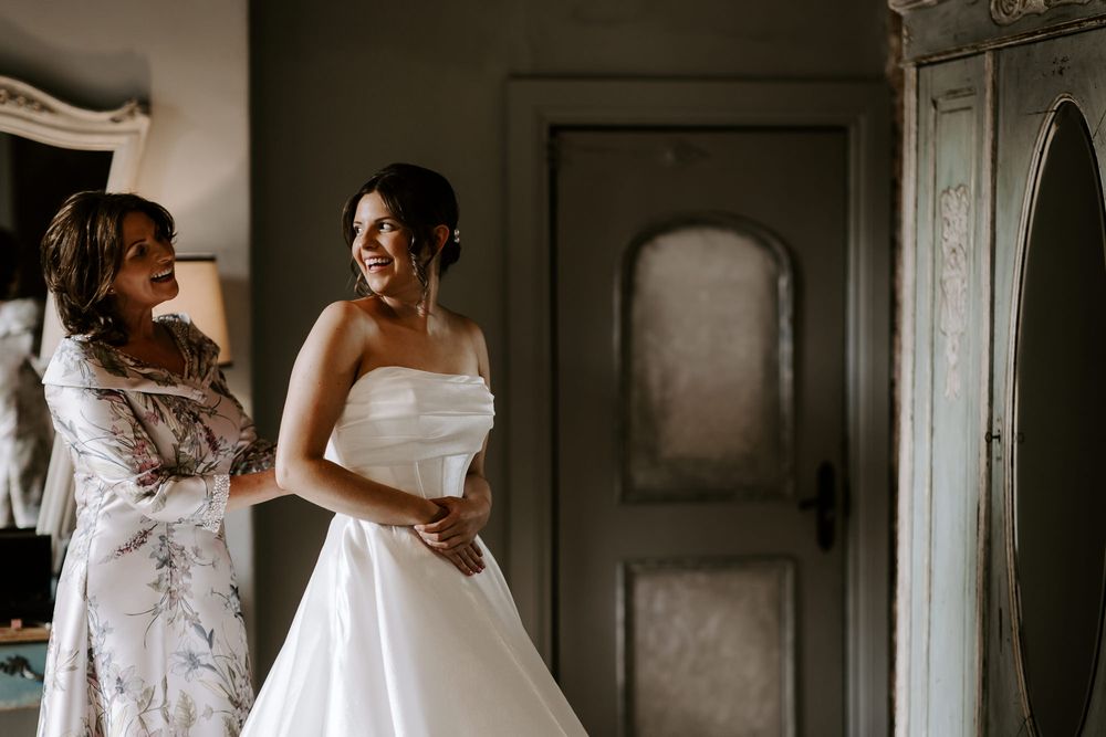 An intimate bridal photoshoot in a rustic indoor setting with natural window lighting.