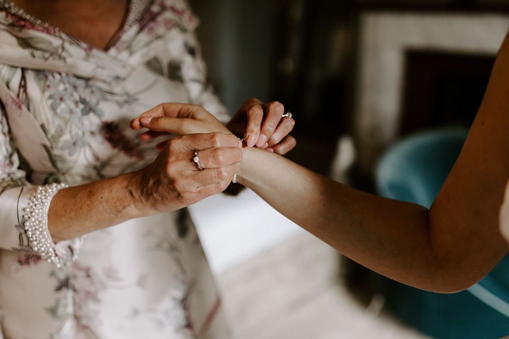 Close up of hands touching and grasping while wearing delicate lace and floral fabric.