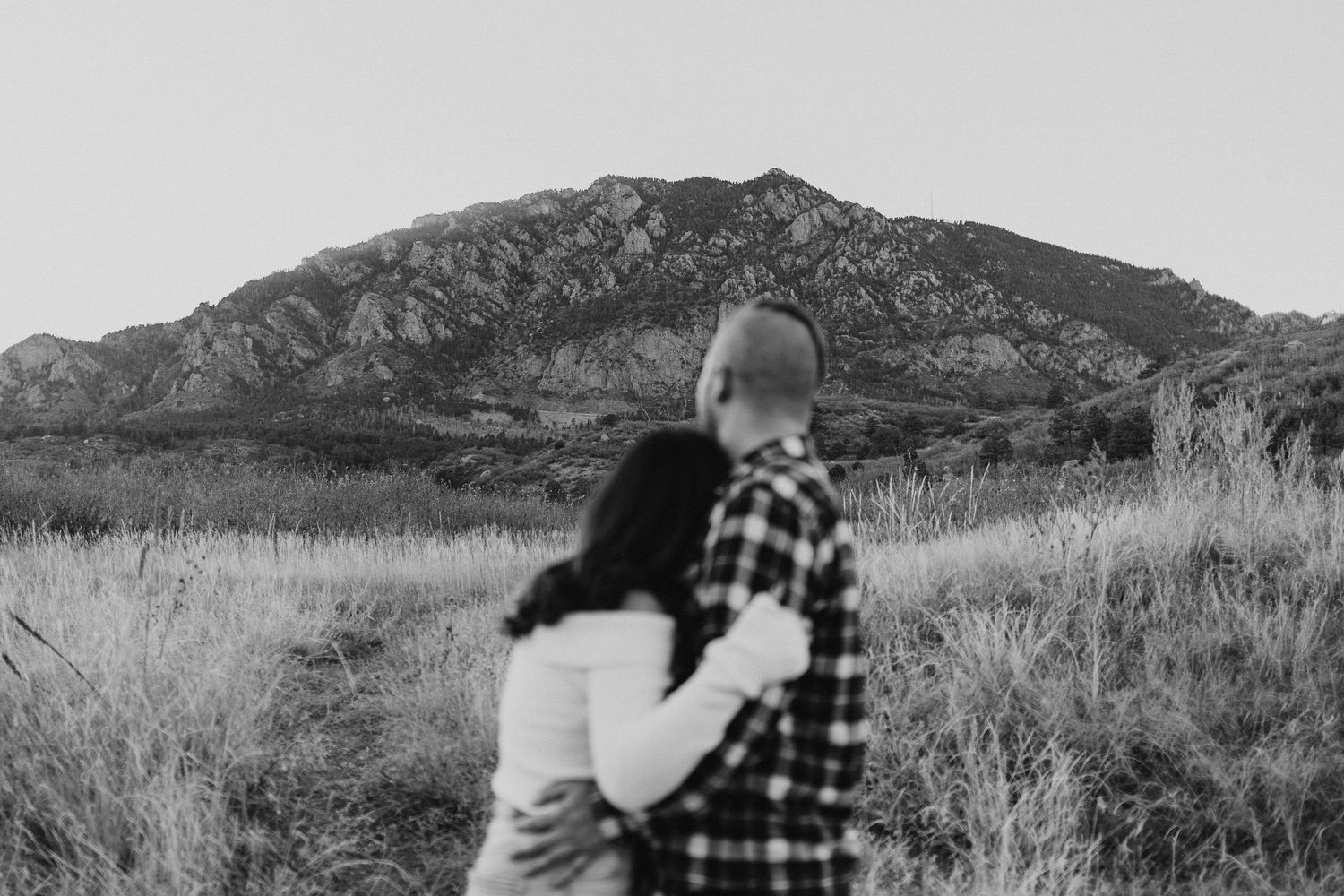 A scenic black and white photo series shows a couple embracing while admiring mountain landscapes in the distance.