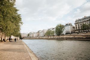 Vue des quais de Seine à Paris avec architecture haussmannienne et ciel nuageux.