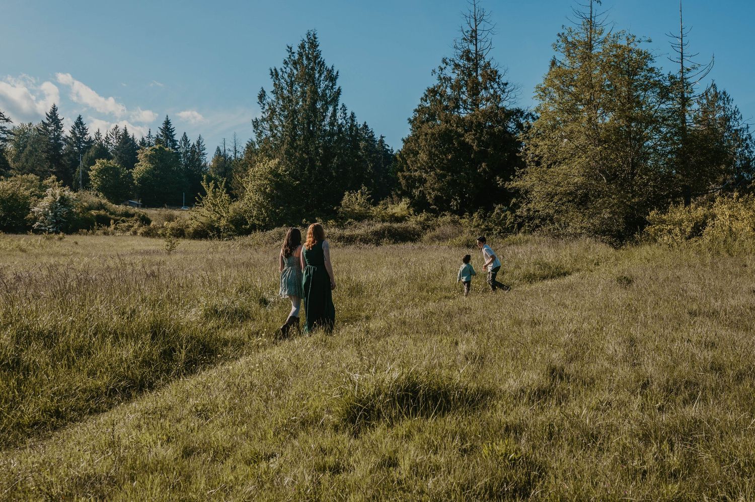 A mother and her children strolling through a field in Howe Farm Park, Port Orchard Washington during golden hour