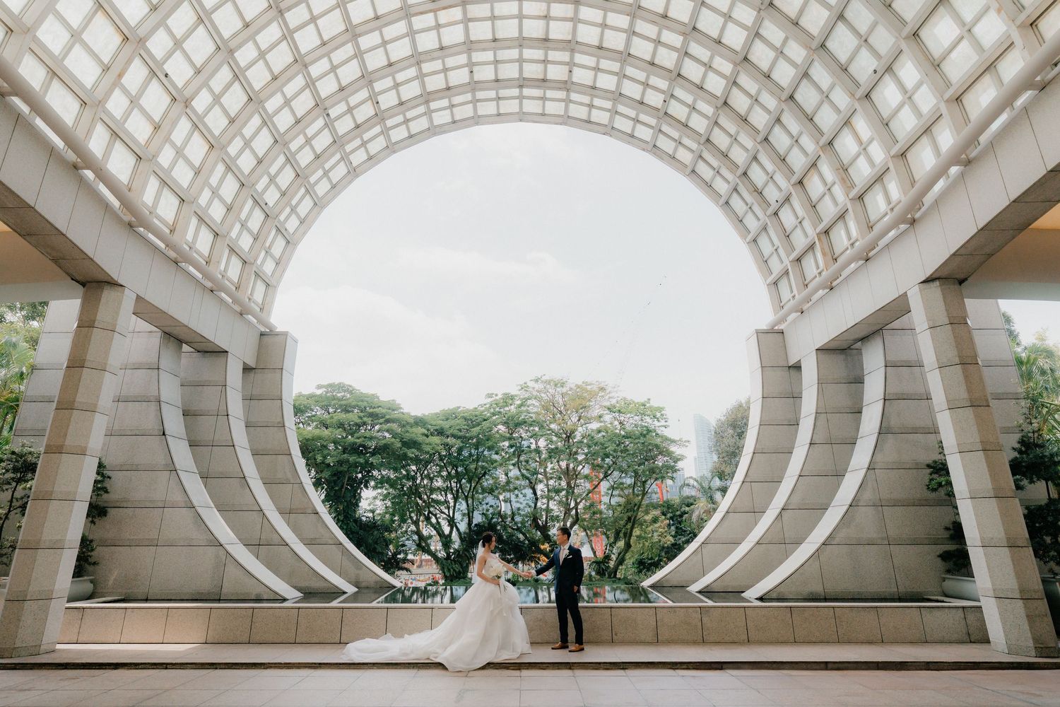 A wedding photo taken under a modern architectural circular archway with geometric patterns.