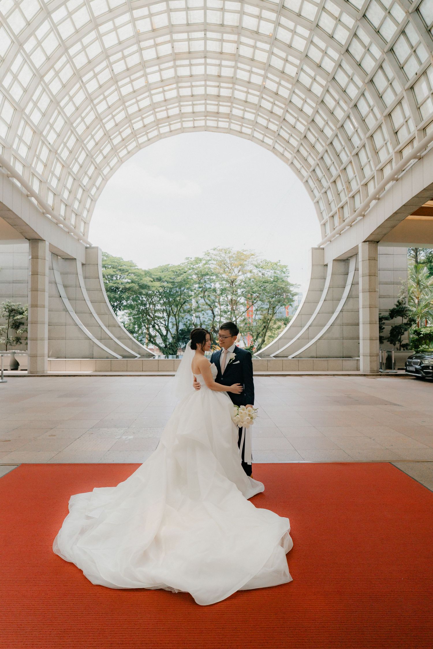 Wedding scene on red carpet under geometric white architectural dome.