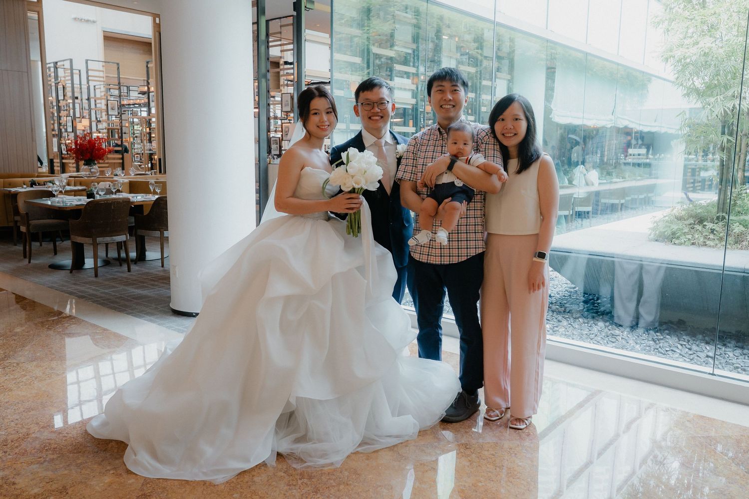 Wedding celebration with a bridal party in formal attire posing together in an elegant venue hallway.