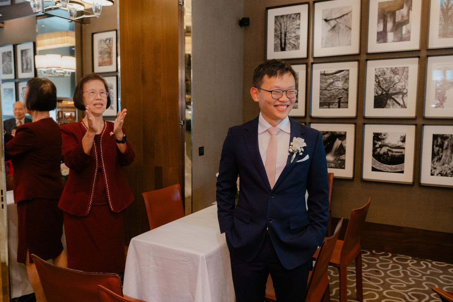 Black and white wedding photographs line the walls of a rustic venue during a celebration.