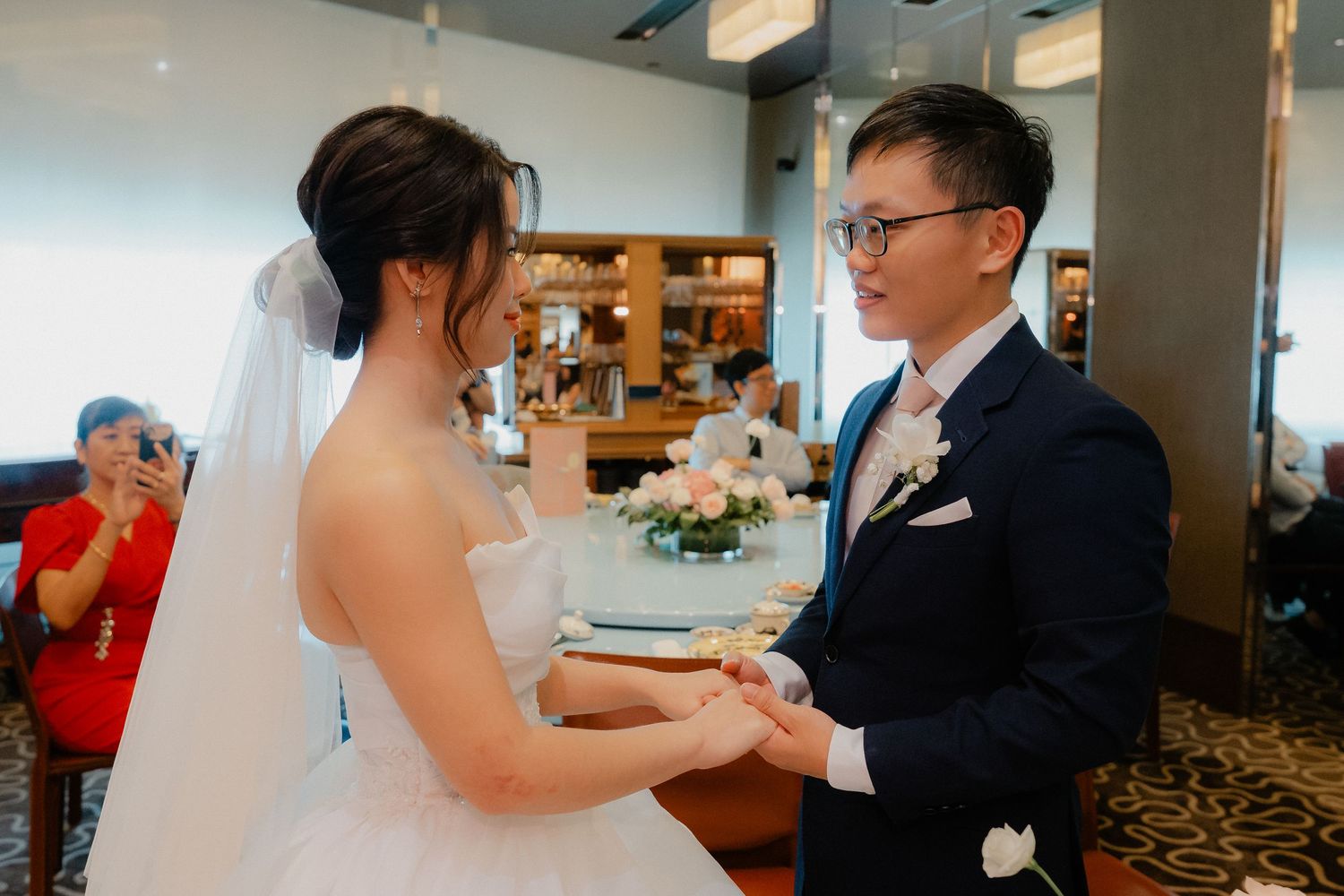 A wedding ceremony in a modern venue with carpeted floors and ambient lighting.