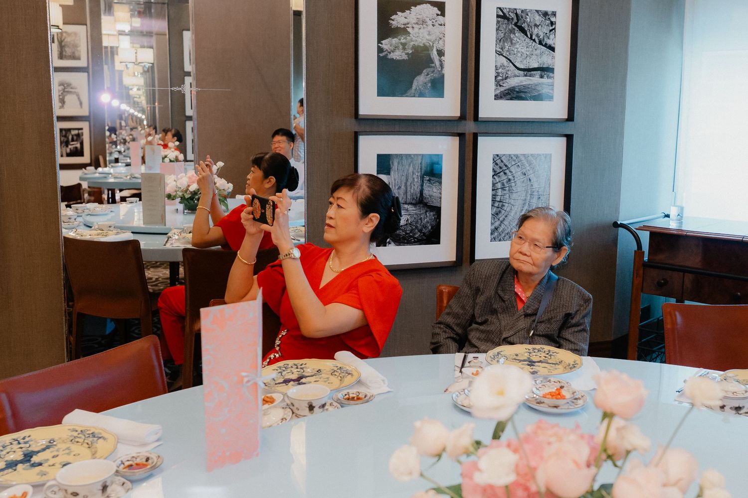 Wedding celebration with guests dining at tables decorated with pink floral centerpieces.