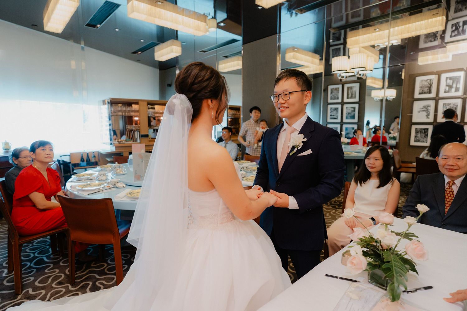 Wedding party dancing and celebrating in a venue with modern blue lighting and casual atmosphere.