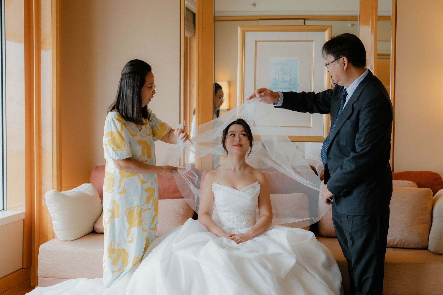 Final wedding preparations in a bright hotel room as veil is adjusted.