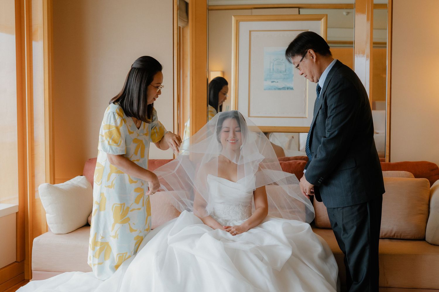 Wedding preparation scene in a hotel room with the bride getting ready in her gown.