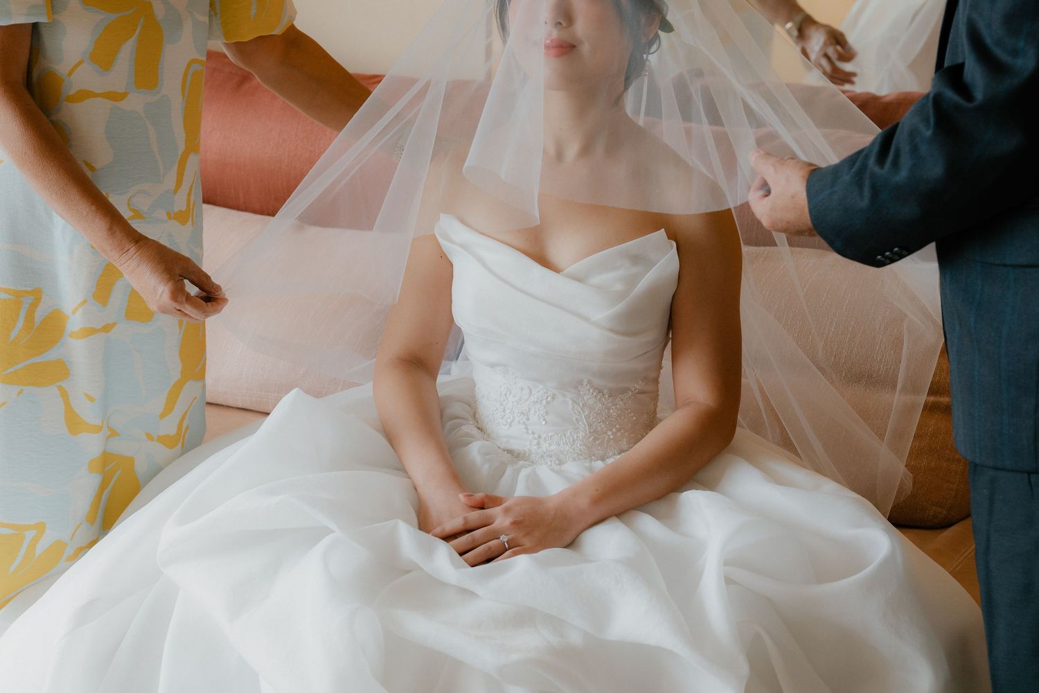 Detailed shot of wedding dress and preparations in golden-hued room.