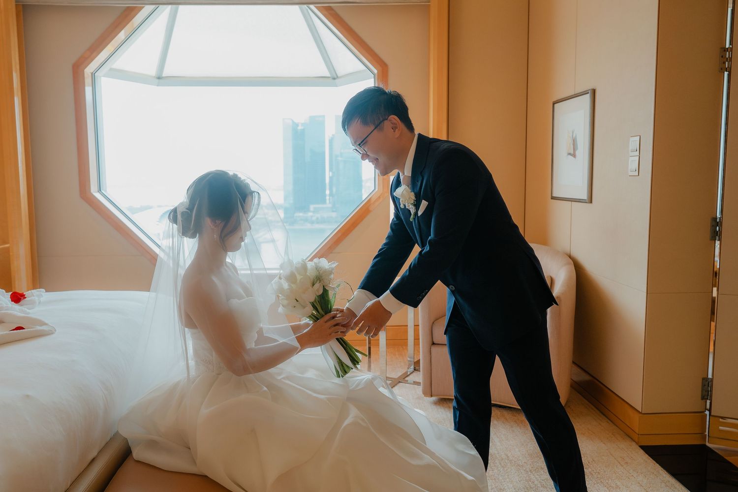 A tender wedding moment captured in a hotel room with an octagonal window.