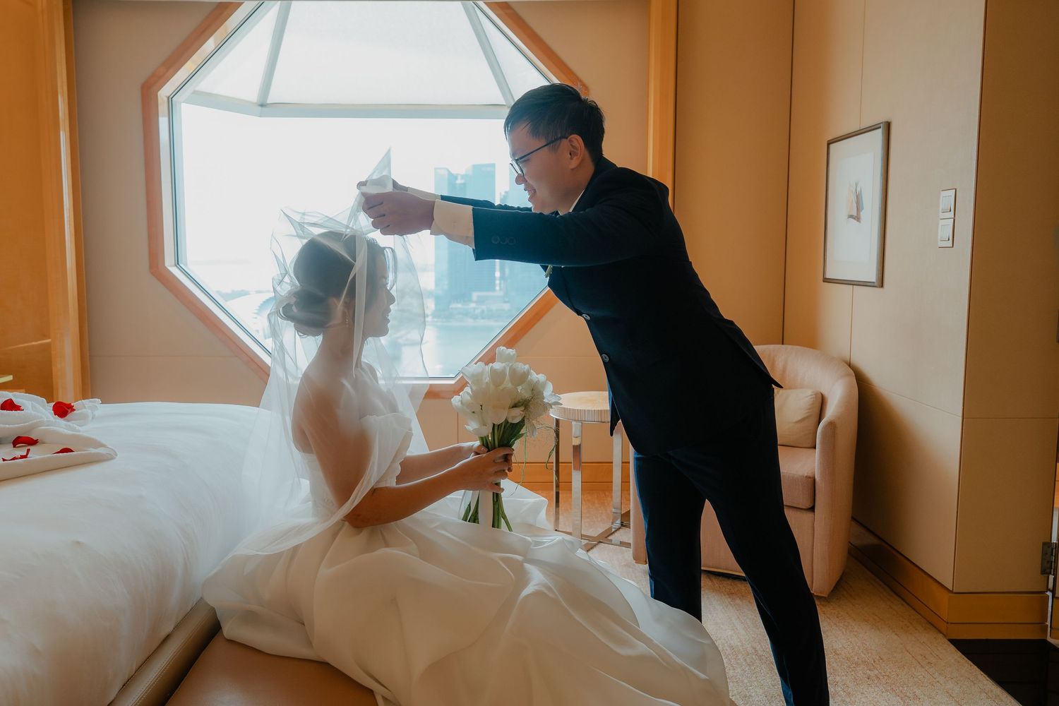 A touching wedding moment captured in a hotel room with warm lighting.