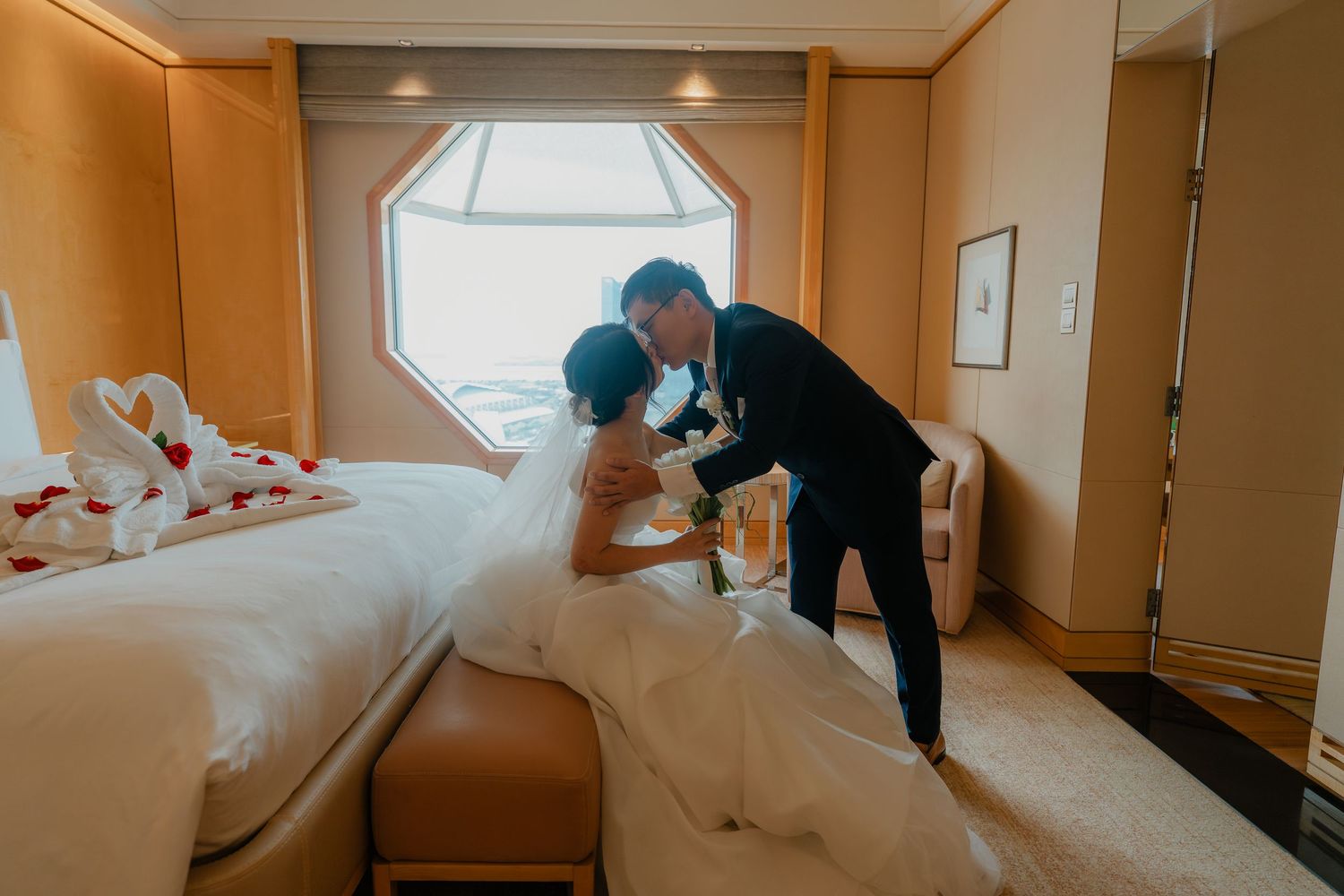 A couple dancing joyfully in a warmly lit indoor venue with elegant decor and lighting.