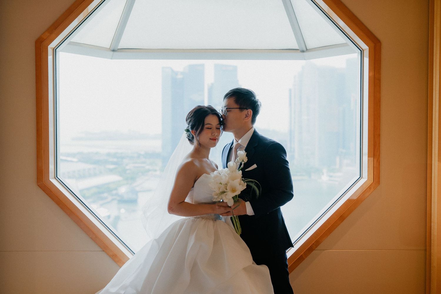 A romantic moment captured against a geometric window with city views.