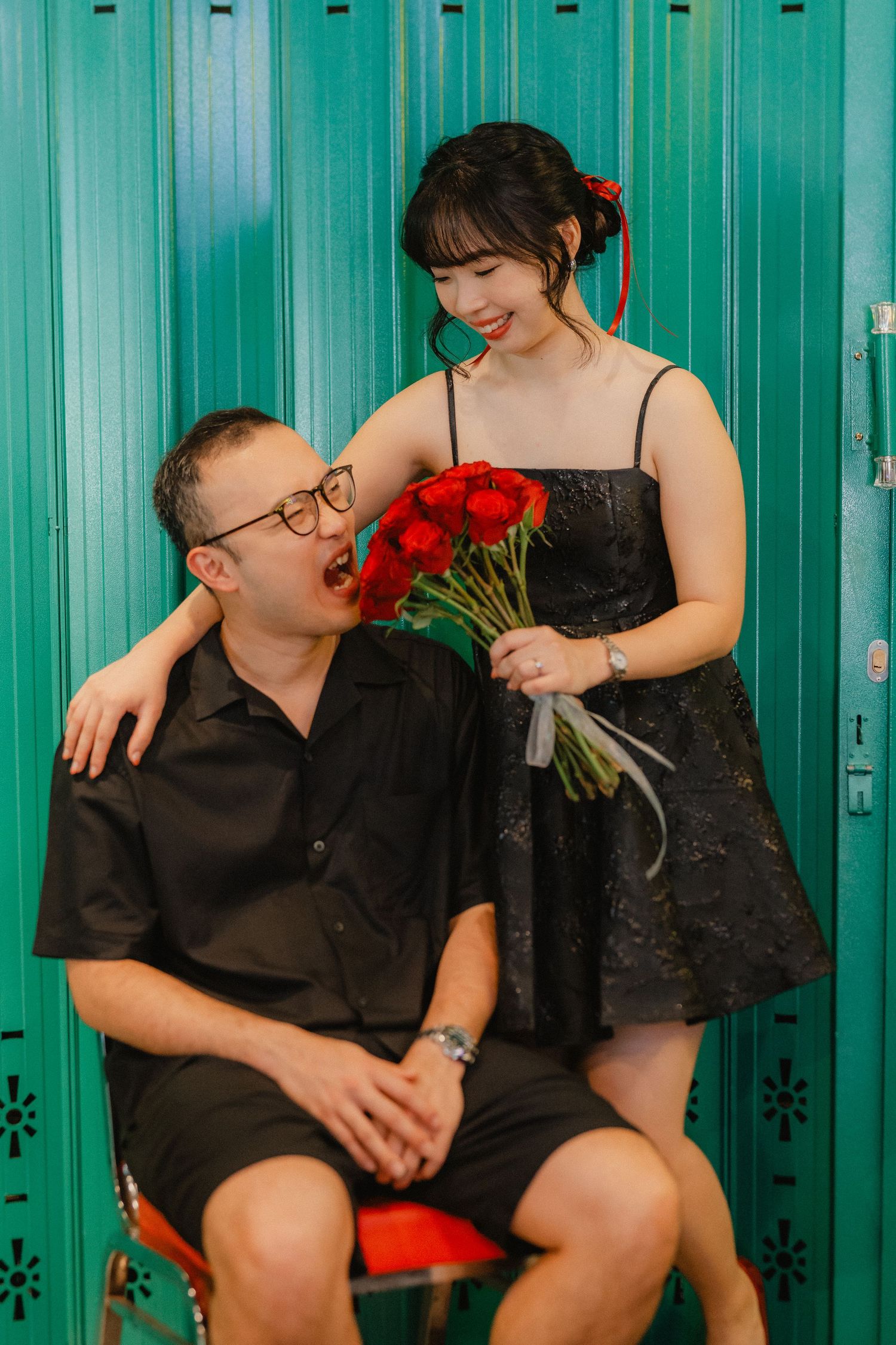 A romantic moment with red roses against turquoise metal lockers.