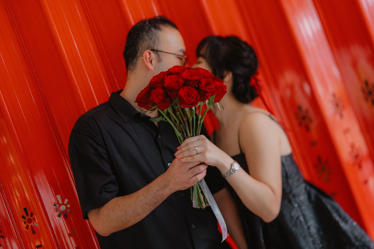 A romantic moment captured with red roses against a vibrant red background.