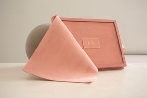 Soft pink linen napkin artfully draped beside a matching pink serving tray on neutral surface.