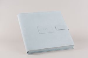 A minimalist white leather photo album or notebook with a clean, modern design lies on a plain background.