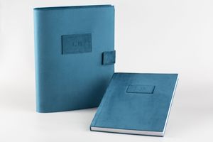 Two light blue leather notebooks or planners with minimalist design and magnetic closures displayed on white background.