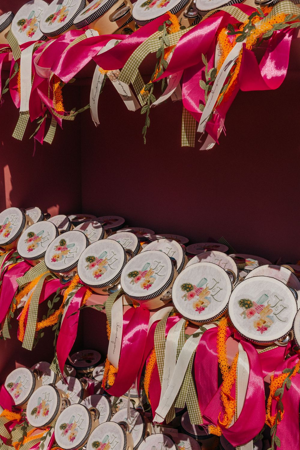 Circular wedding favors with floral designs arranged in rows with bright pink and orange ribbons.