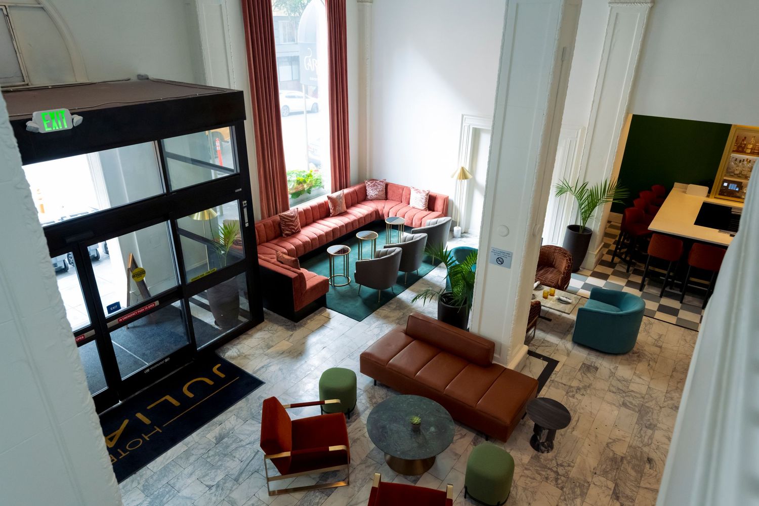 Modern open concept living room and dining area with hardwood floors, white walls, and large windows letting in natural light.