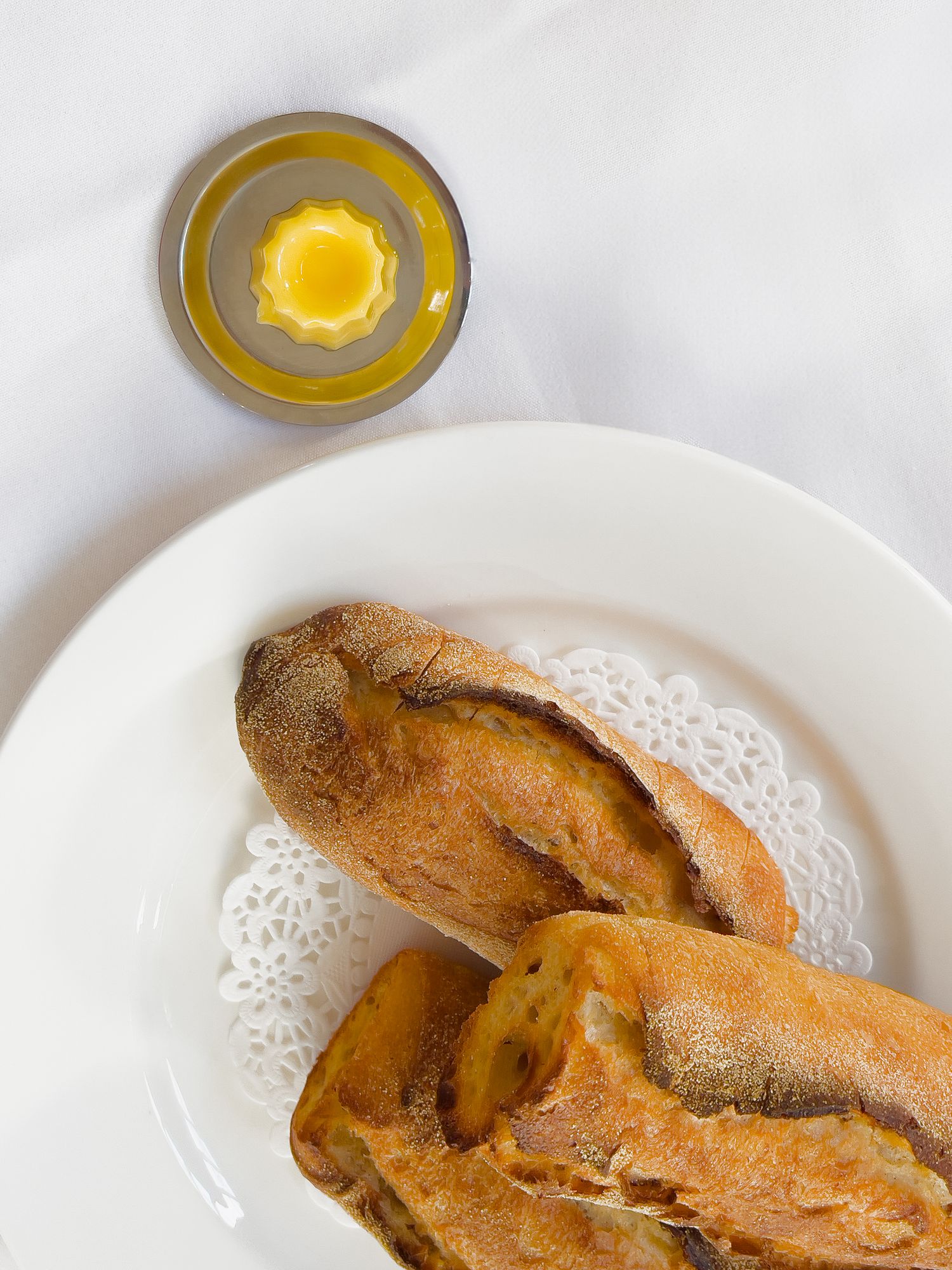 A sliced loaf of rustic bread displayed on white plates photographed from multiple angles.
