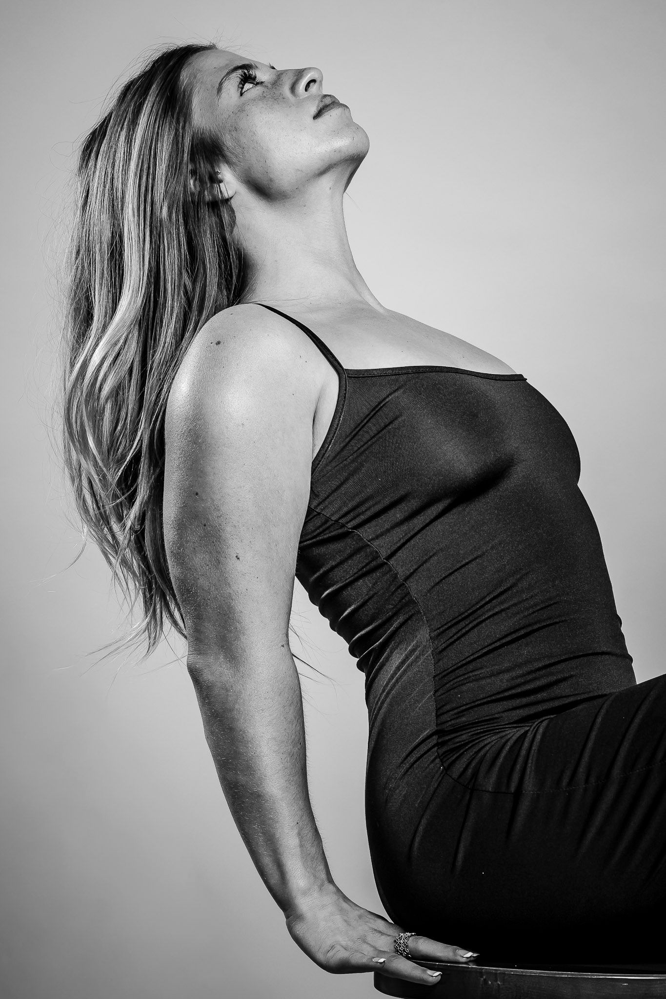 Black and white photo of a woman in a black dress leaning back gracefully with her head tilted upward.