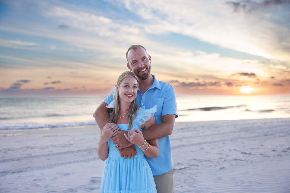 Family portrait at sunset on a beautiful beach with matching blue and white outfits.