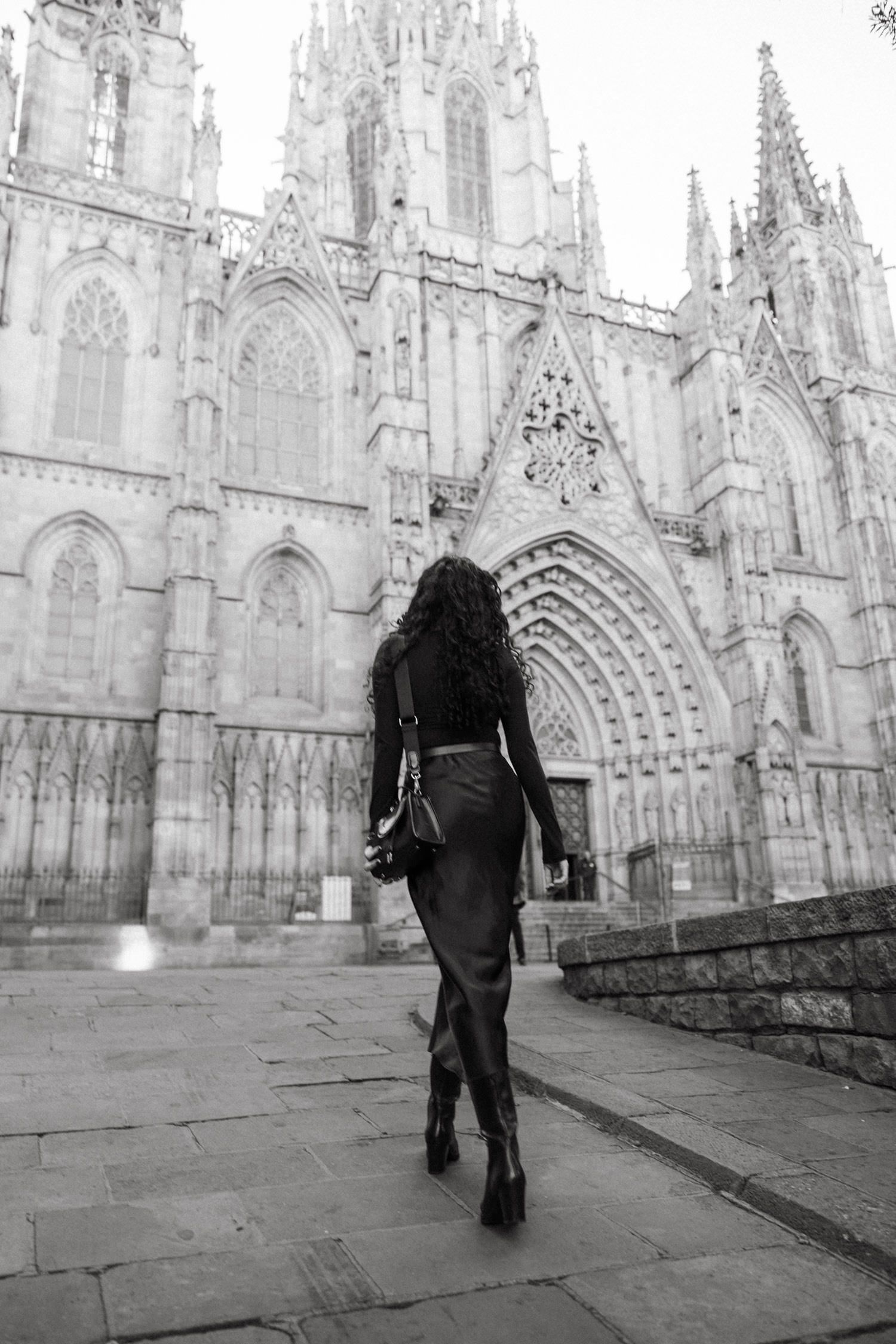 Gothic cathedral facade with ornate stone architecture and arched doorways in black and white.